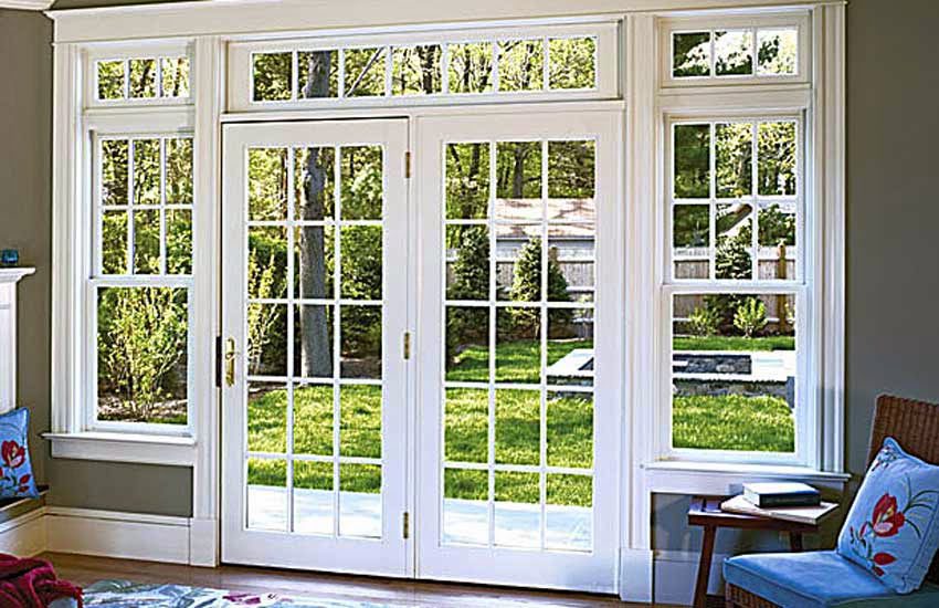 Large white-framed patio doors opening to a garden with green grass and trees.