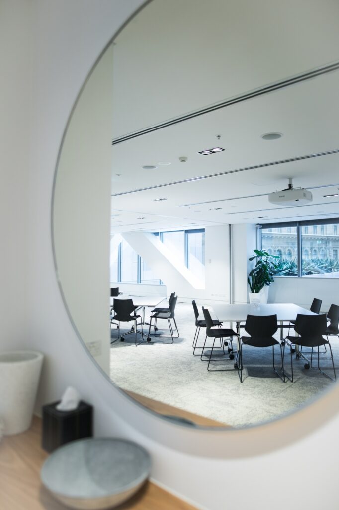 Round mirror in a conference room featuring chairs and tables, branded with Clearview Windows & Doors.